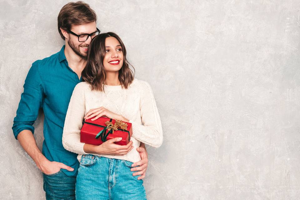 Couple of man and woman smiling and holding a red gift box