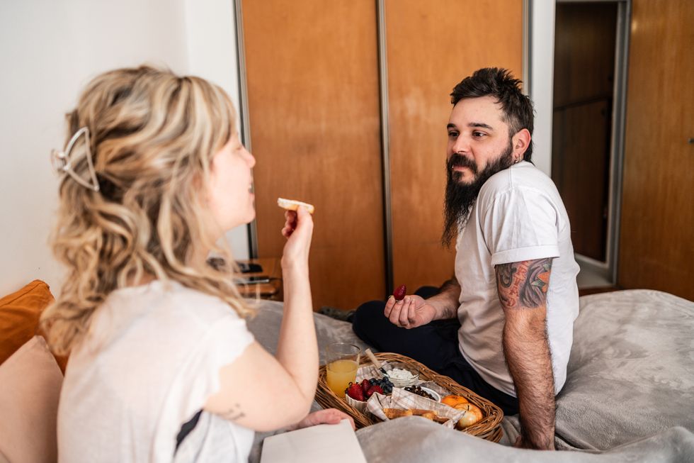 couple talking and having breakfast in bed at home